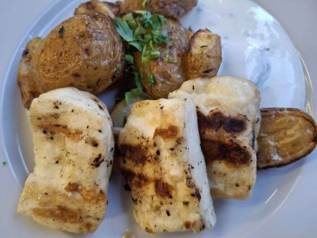 Grilovaný sýr halloumi podávaný s bramborem ve slupce a k tomu s česnekovým dipem podobným tzatziki.